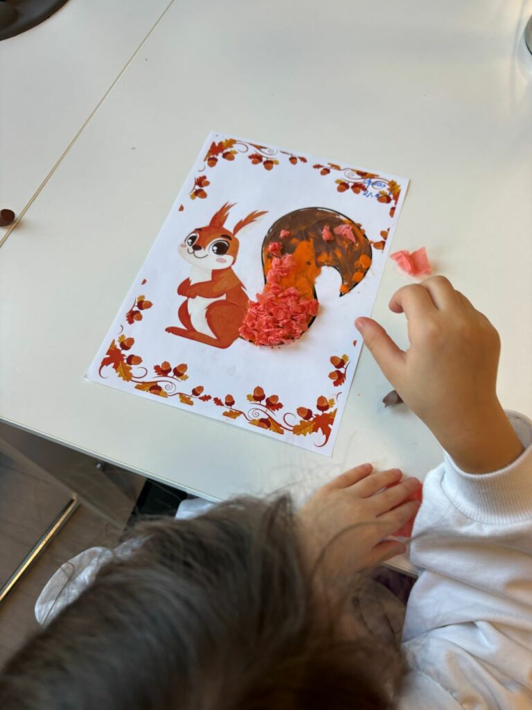 Na zdjęciu widać przedszkolaka wykonującego pracę plastyczną przedstawiającą wiewiórkę.
