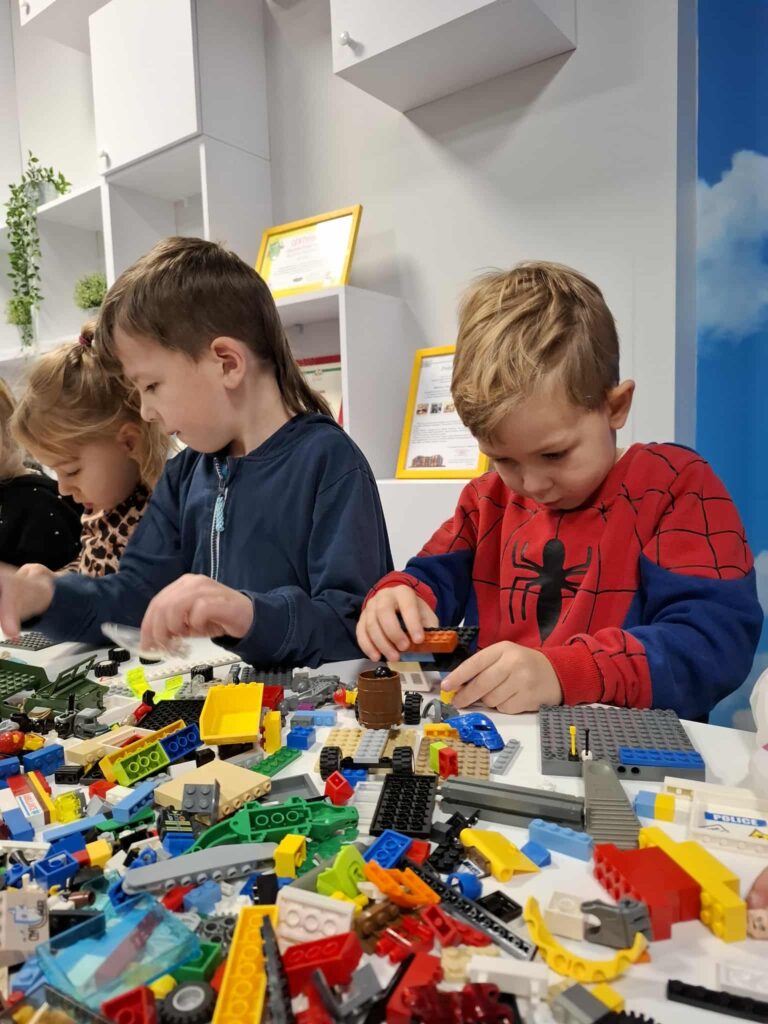 Na zdjęciu przedszkolaki, które budują z klocków Lego.