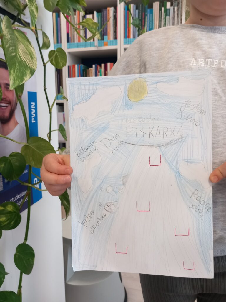 Dziewczynka trzyma w dłoniach swoją pracę plastyczną wykonaną kredkami.