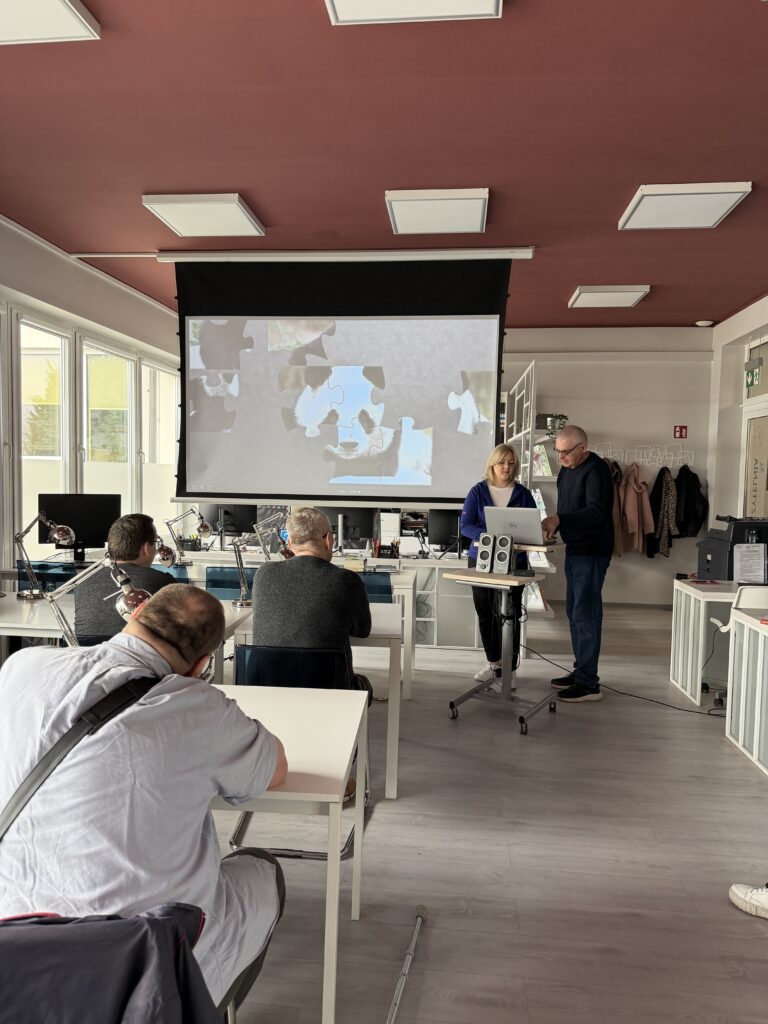 zajęcia z dorosłymi w czytelni, uczestnik układa puzzle wyświetlone na dużym projektorze - obrazek pandy 