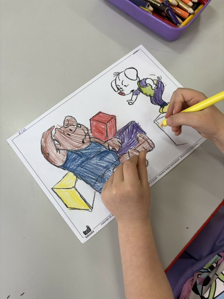 Na zdjęciu widać dziecko siedzące przy stoliku, które koloruje kredkami ilustrację.
