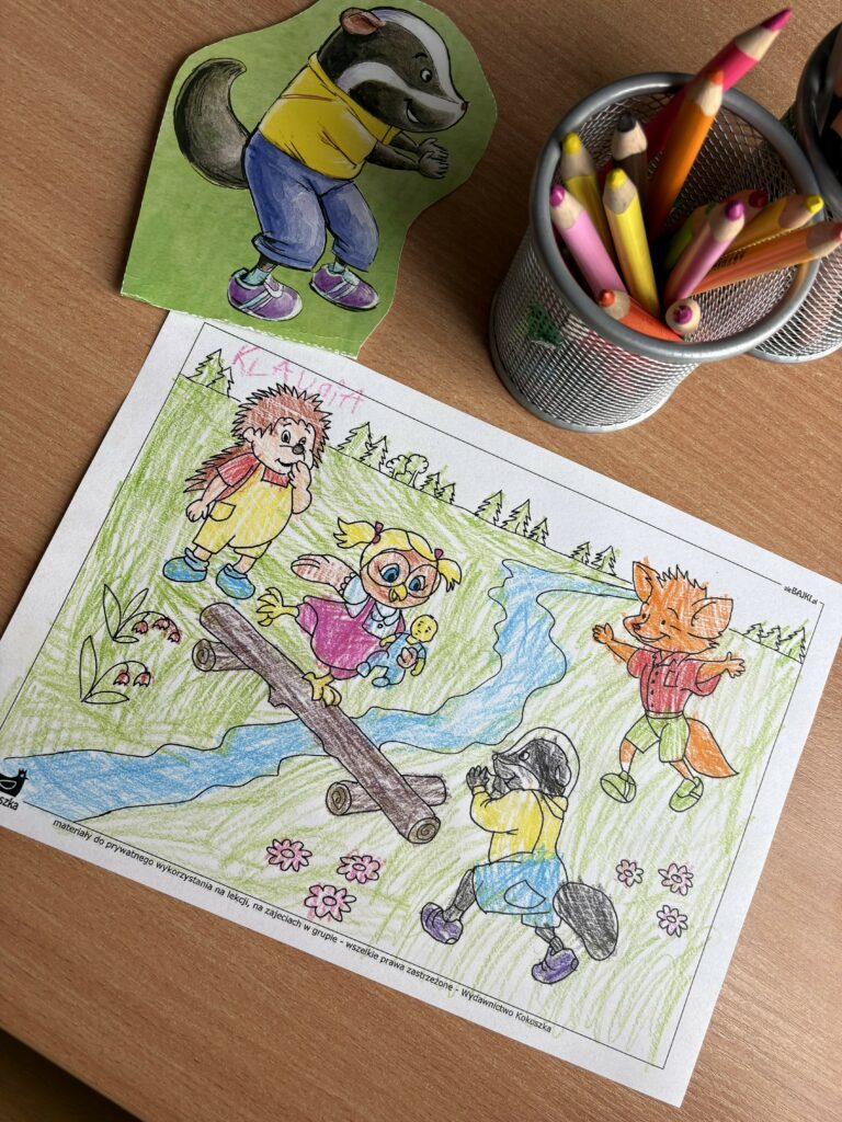 Na zdjęciu widać pokolorowaną ilustrację przedstawiającą bohaterów bajki "O borsuku, który na cały świat się obraził" oraz kredki.